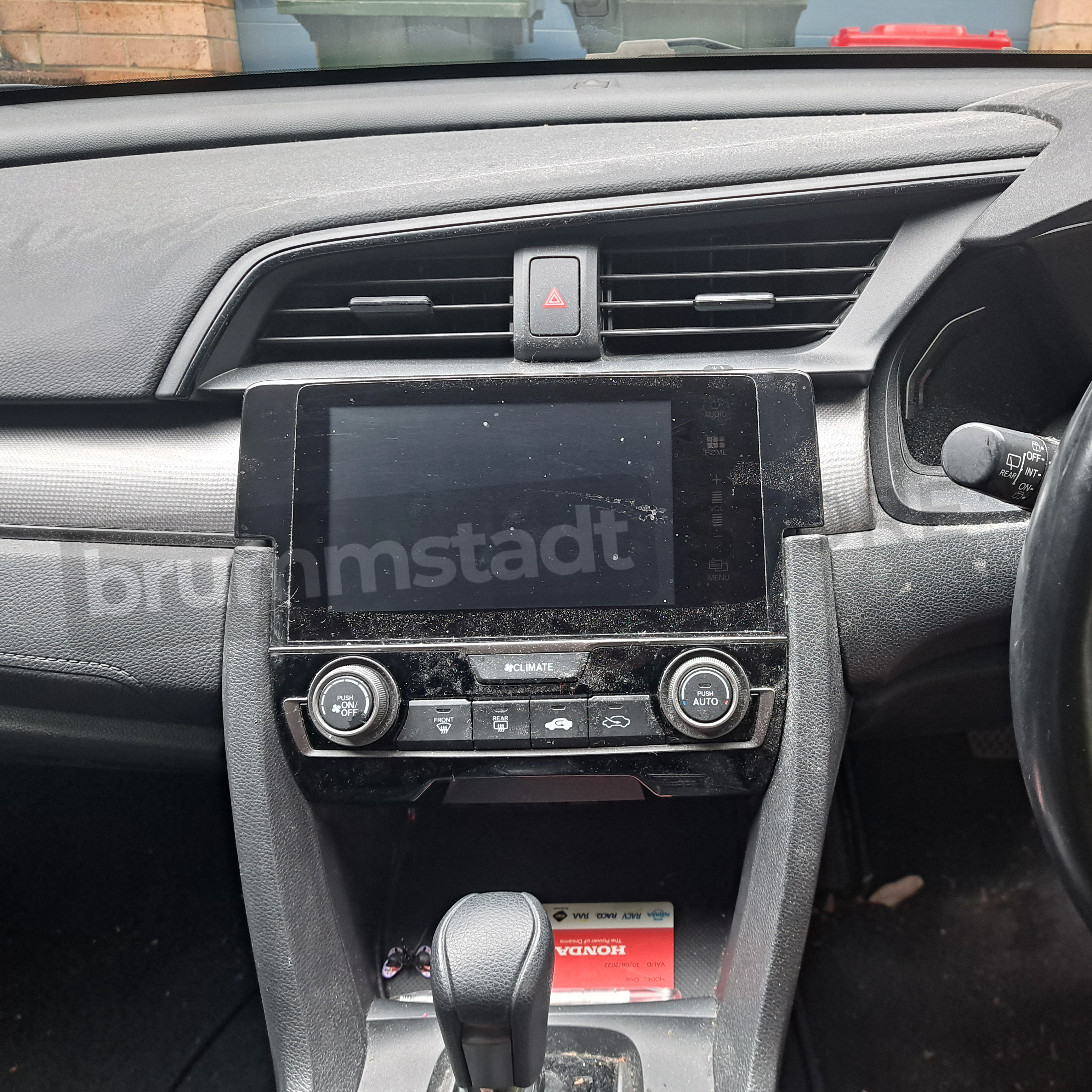 Brummstadt showing factory head unit t of Honda Civic 2016-2018, black touchscreen display with infotainment controls, no visible UI, featuring buttons for climate control and audio adjustments in the Honda Civic interior.